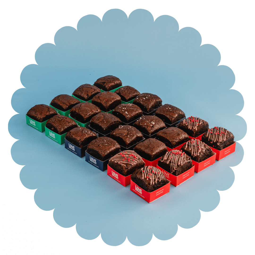 An open gift box displaying various bags of brownie bites with different flavors such as double chocolate, caramel fudge, salted caramel, and more.