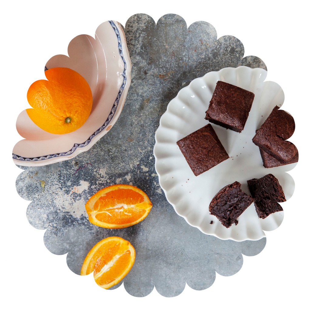 Moist chocolate brownies with orange oil on a plate and fresh oranges