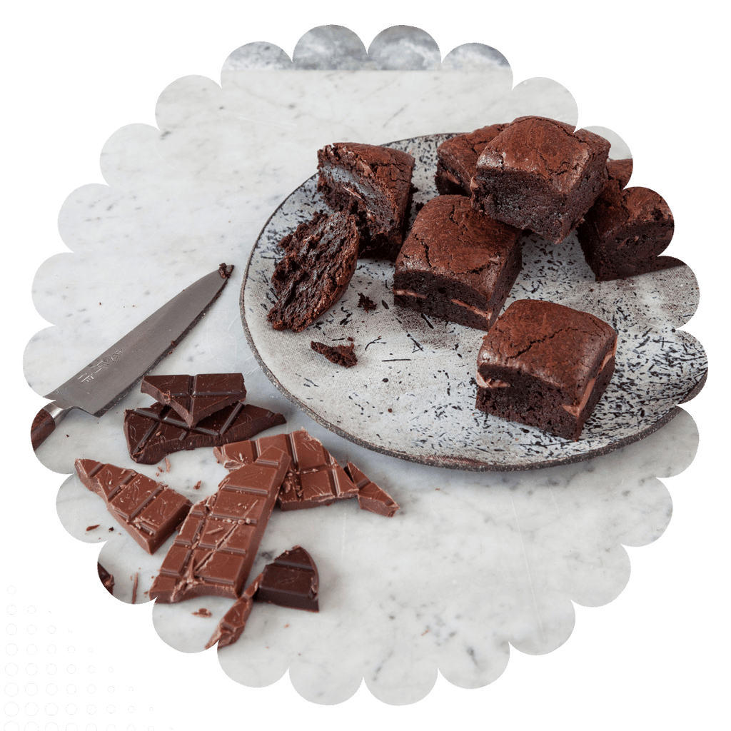 Double chocolate gluten -free brownies stacked on a plate with broken chunks of milk chocolte and dark chocolate