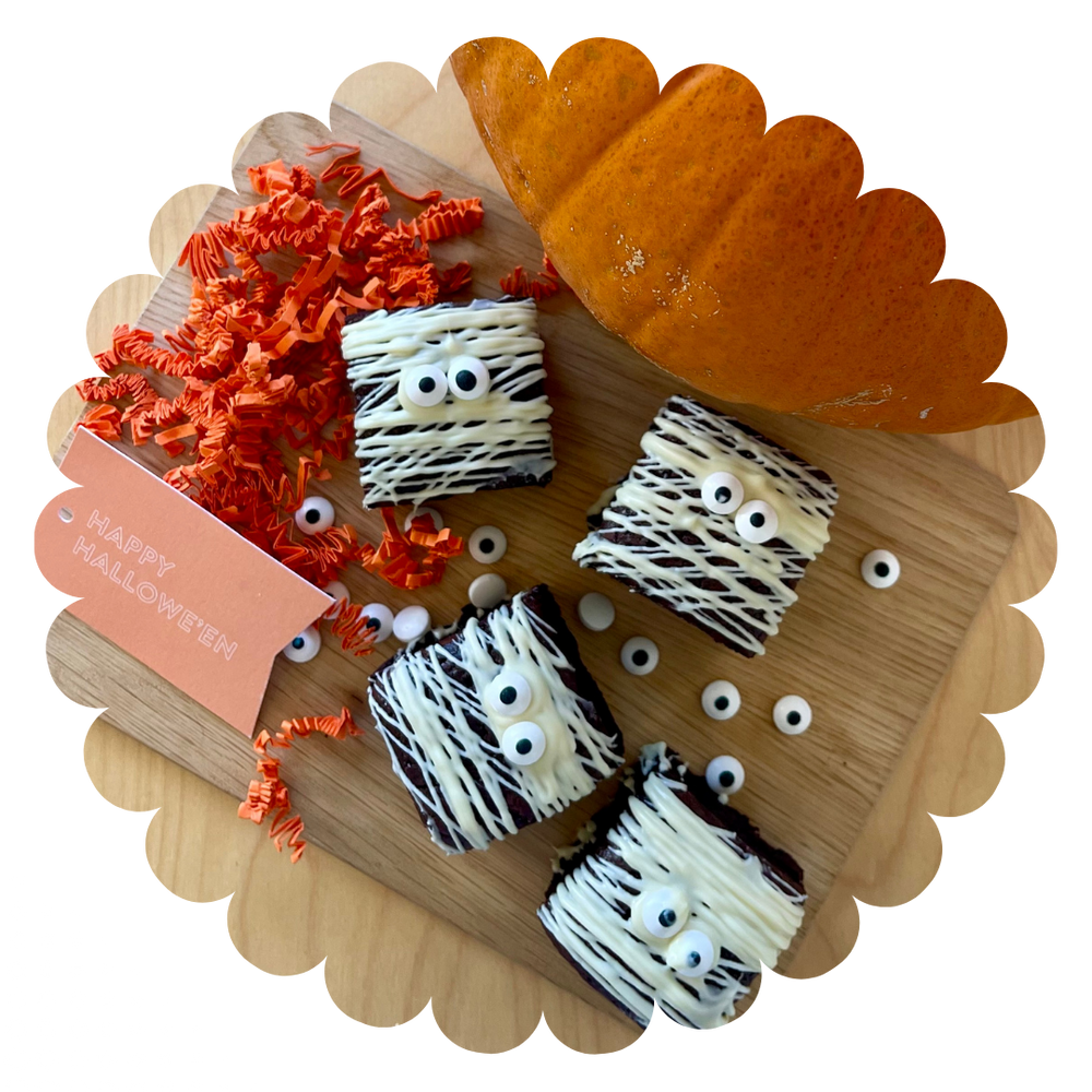 
                  
                    4 double chocolate gluten-free brownies with white chocolate drizzle to look like bandages and googly eyes. On a tray with a pumpkin and Happy Halloween gift tag
                  
                