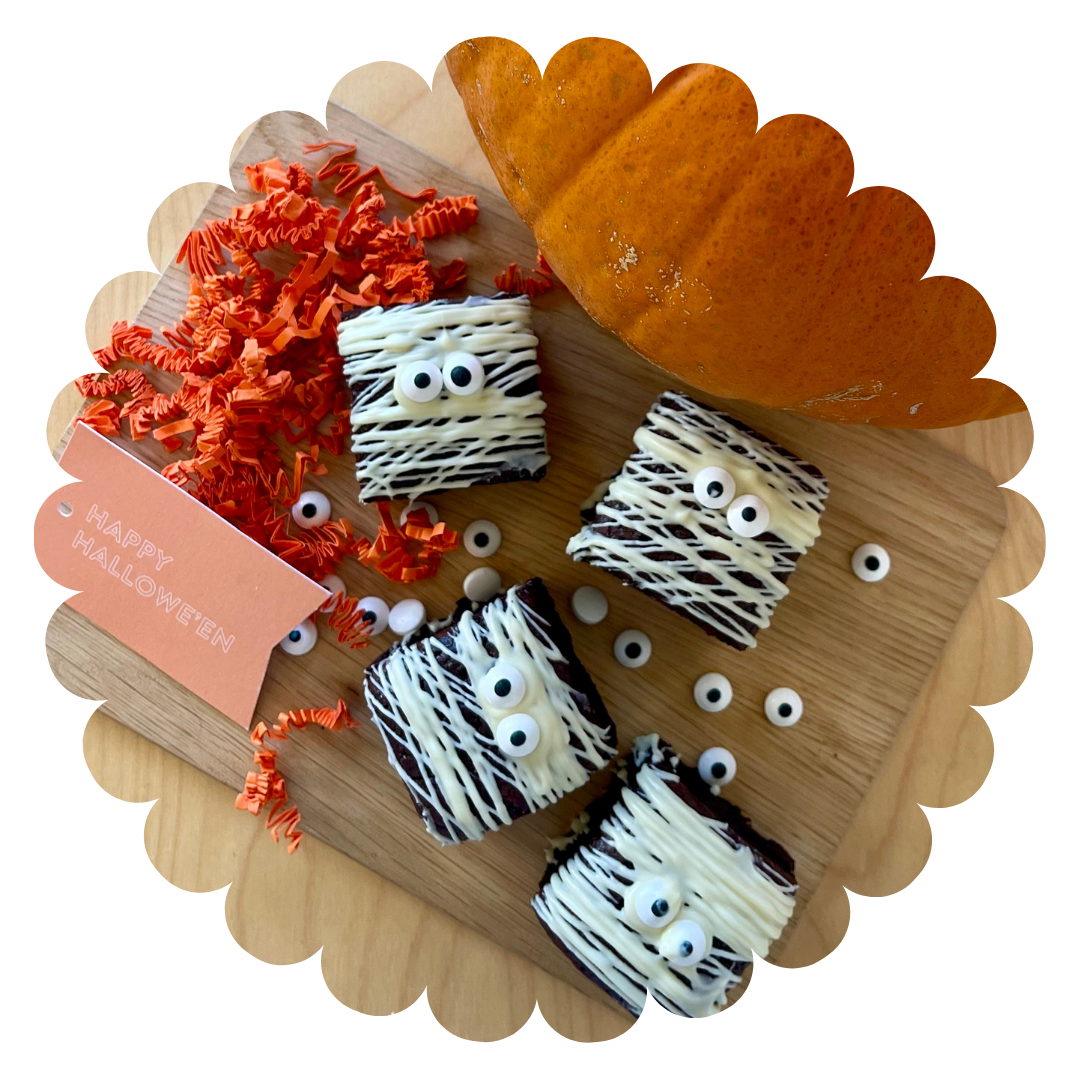 
                  
                    4 double chocolate gluten-free brownies with white chocolate drizzle to look like bandages and googly eyes. On a tray with a pumpkin and Happy Halloween gift tag
                  
                