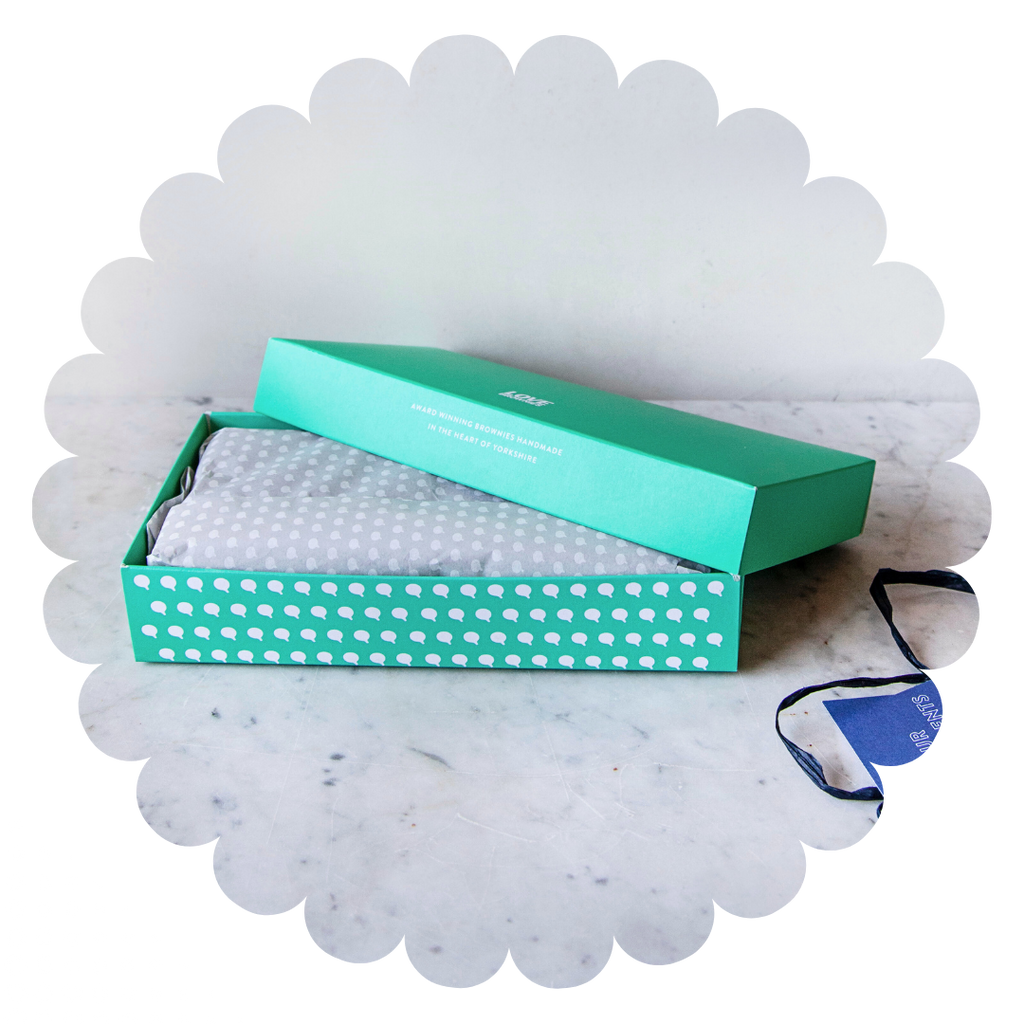 A box of 8 gluten free handmade brownies from Love Brownies in a colourful box and wrapped with paper. 