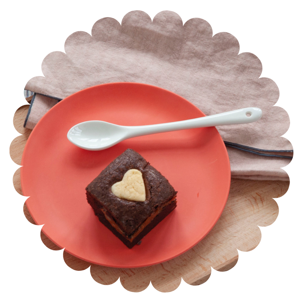 fresh raspberry and ruby chocolate gluten-free brownie with a shortbread heart on a red plate