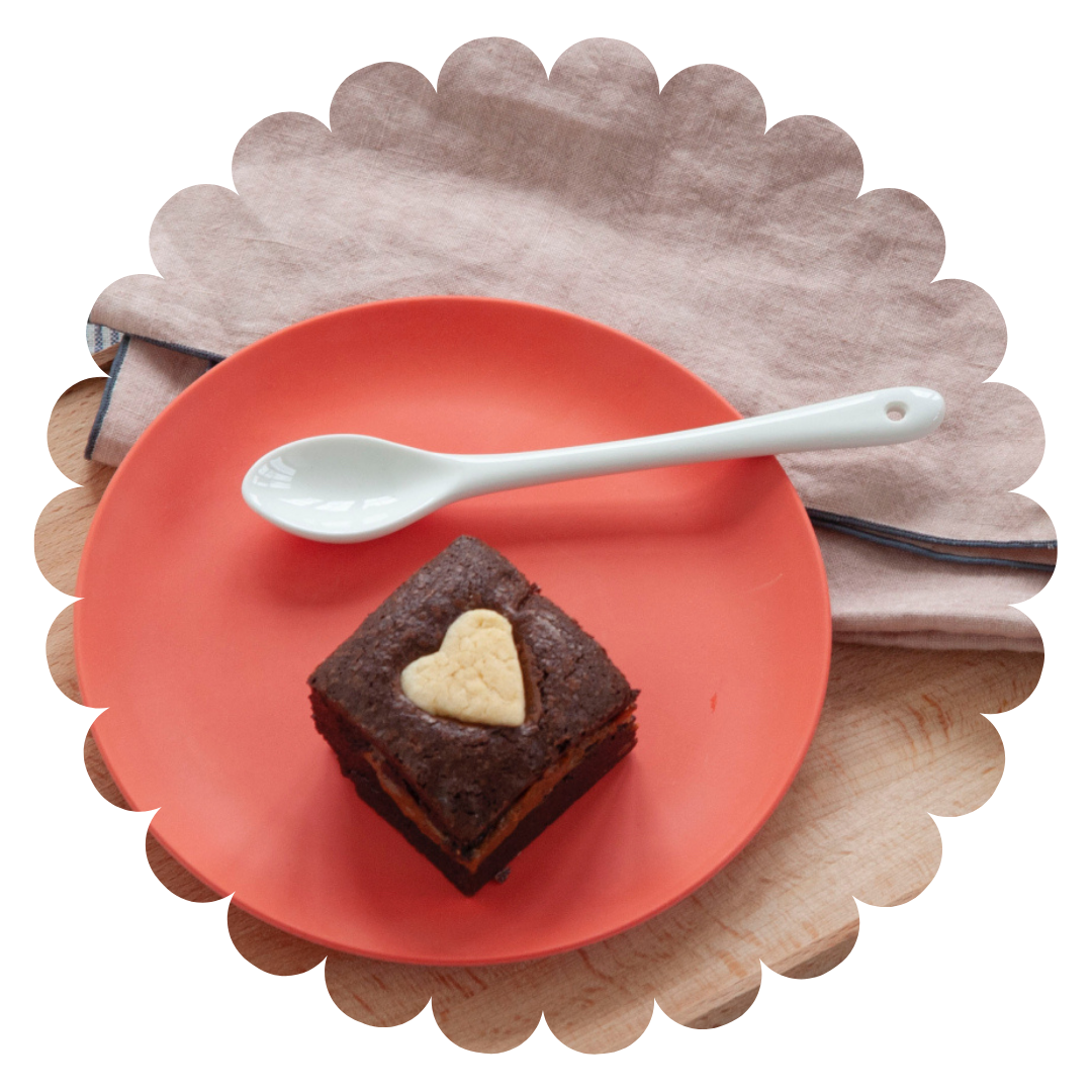 fresh raspberry and ruby chocolate gluten-free brownie with a shortbread heart on a red plate