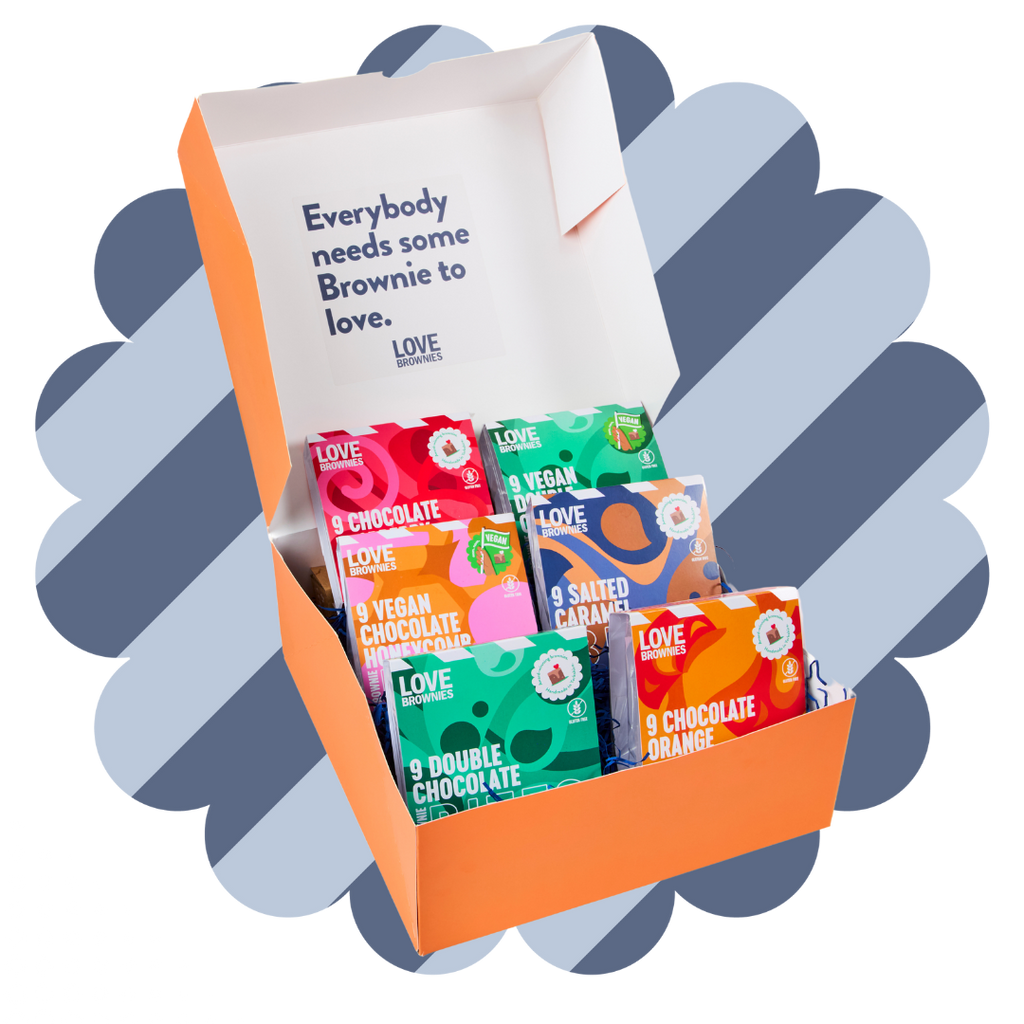 An open gift box displaying various bags of brownie bites with different flavors such as double chocolate, caramel fudge, salted caramel, and more.