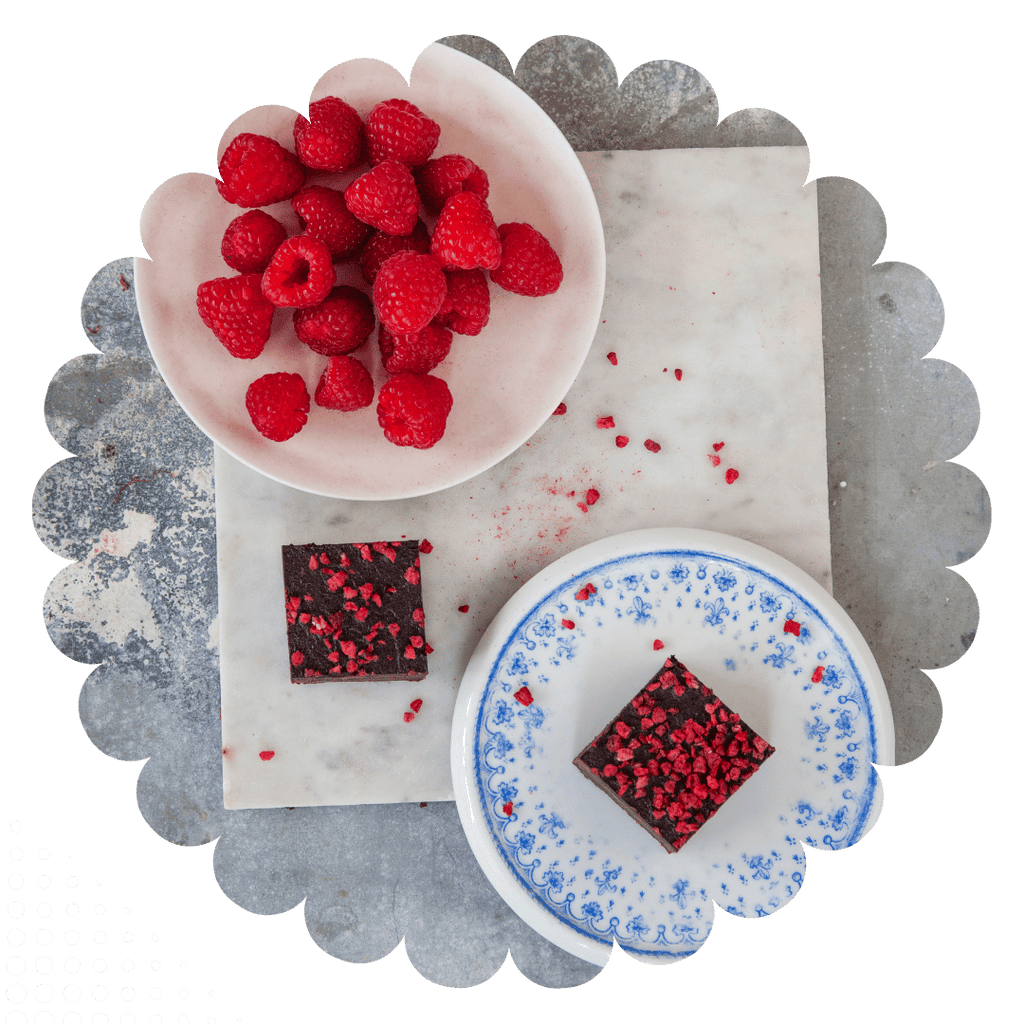 Dairy free, egg free, gluten free, nut free raspberry brownies with freeze dried raspberry topping on a marble surface with raspberries.